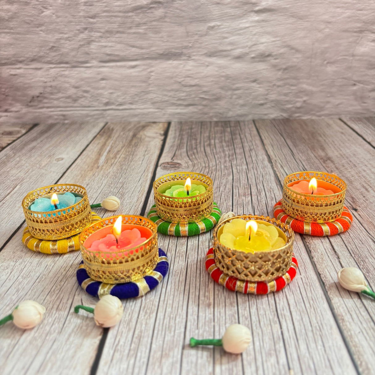 Colorful lit tealight candles in decorative gold holders for home and festive decor