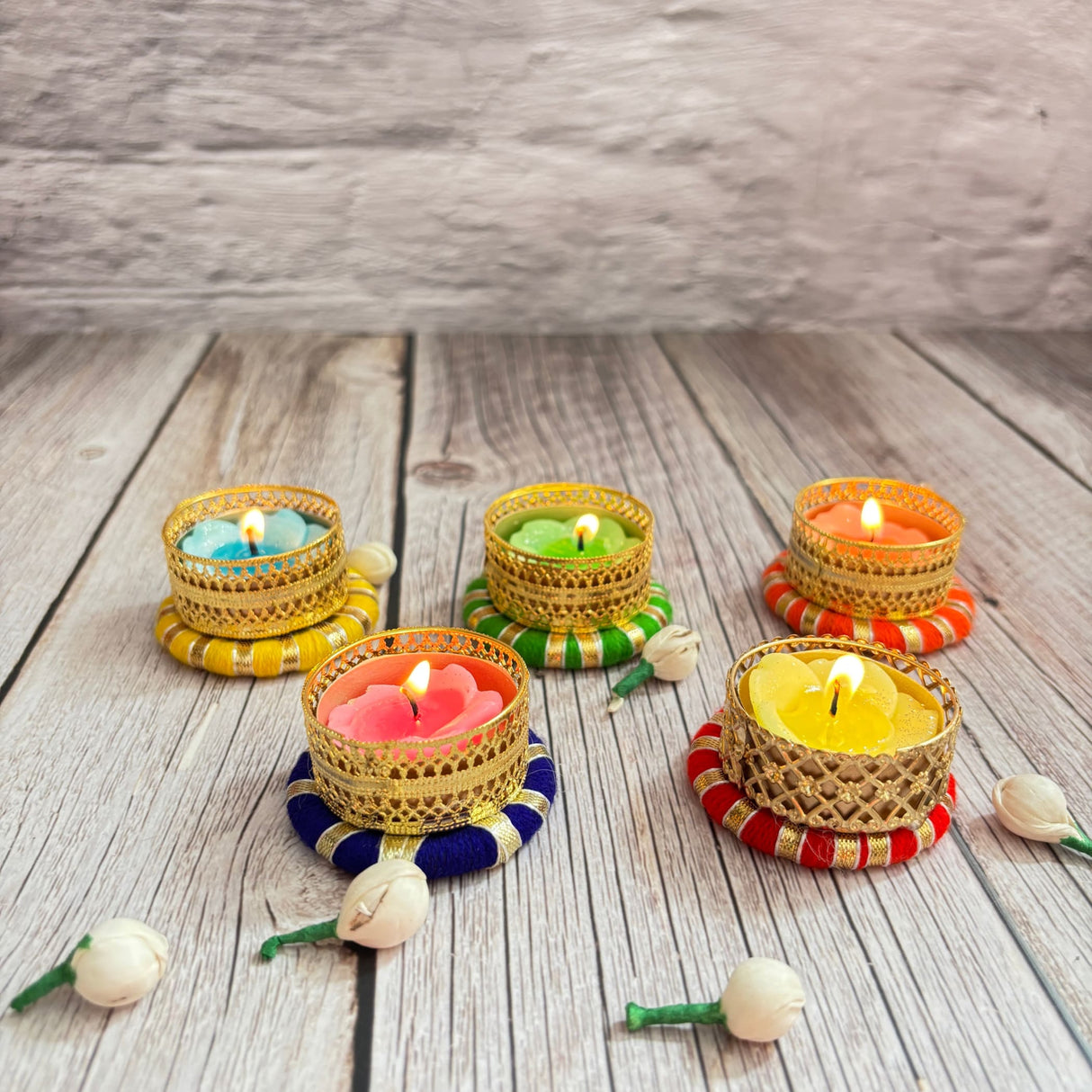 Five lit ornate golden tealight candle holders with colorful bases for festive decor