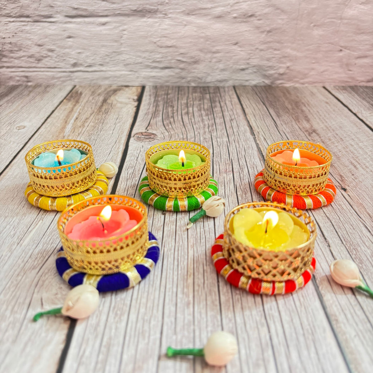 Five colorful lit tea light candles in ornate golden holders for festive and home decoration