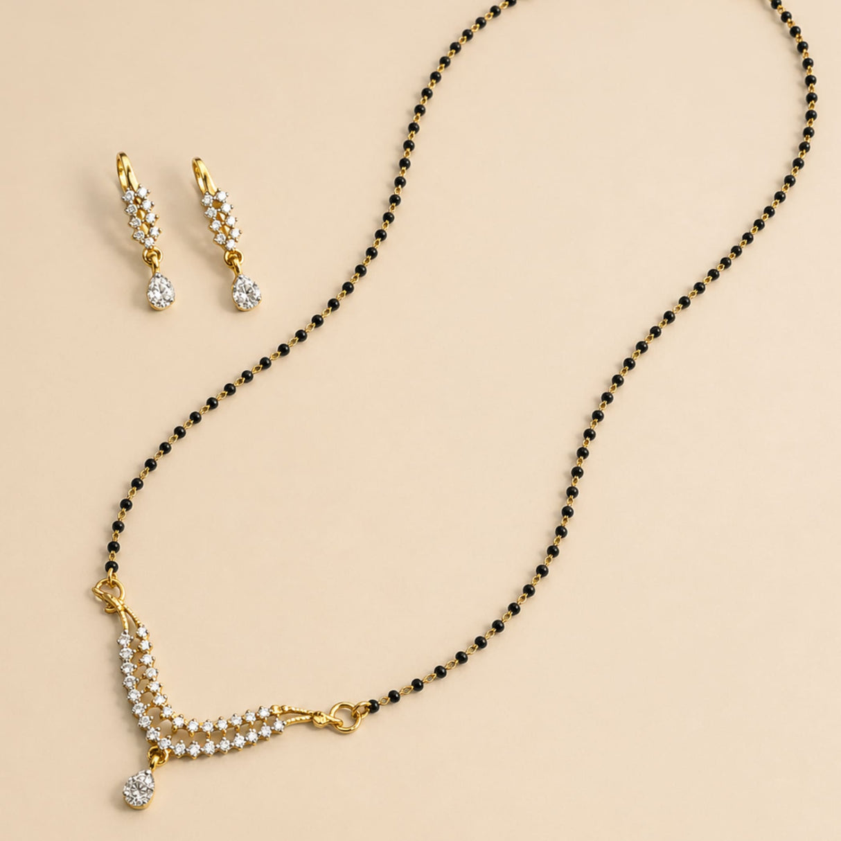 Gold-plated mangalsutra with black beads and clear stones paired with matching earrings for Indian bridal jewelry gift