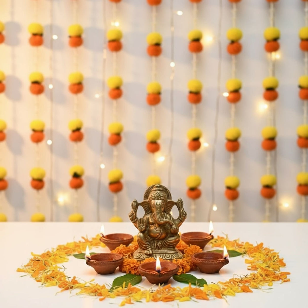 Brass Ganesha idol with oil lamps and marigold petals for Diwali decoration