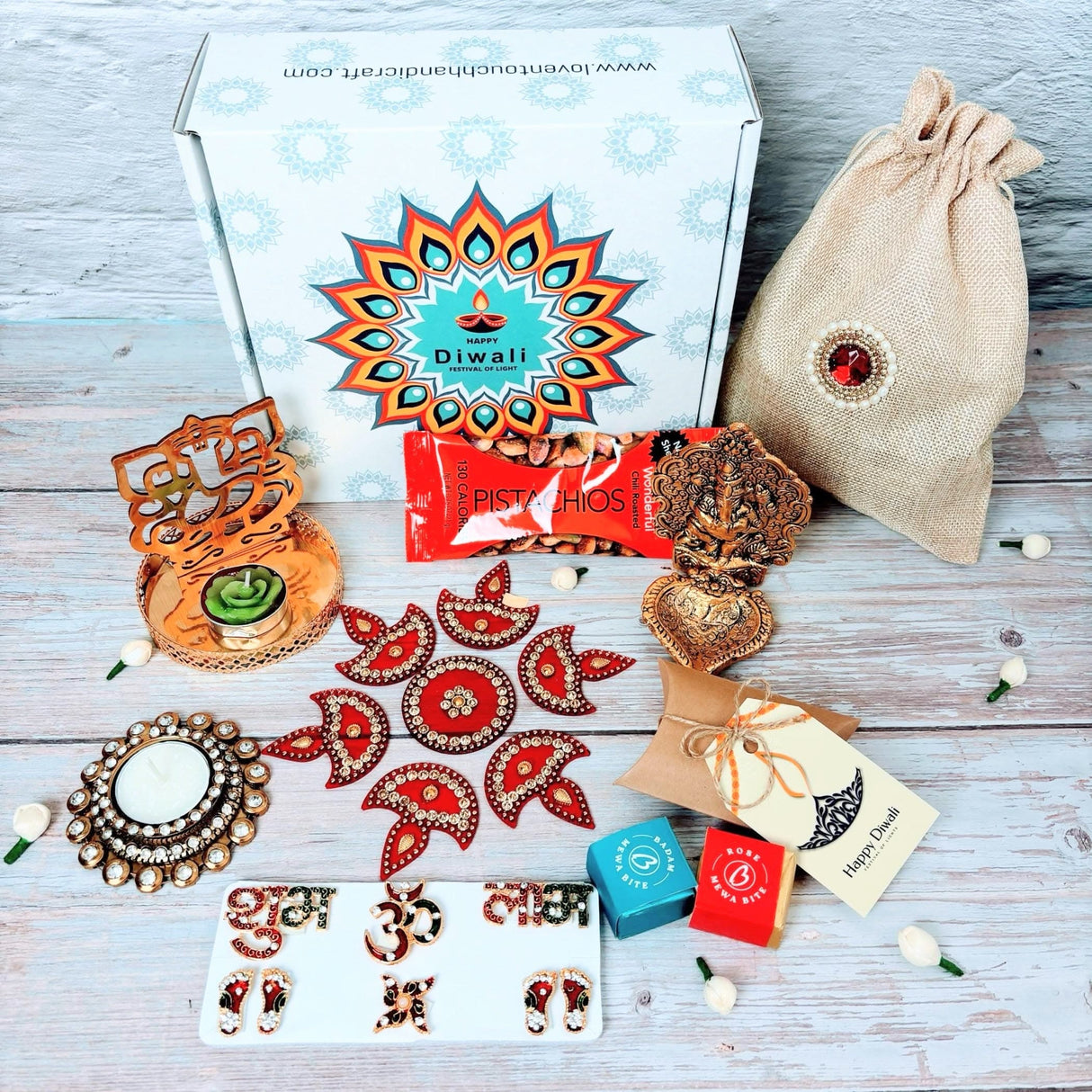 Diwali gift box with decorative items, sweets, and pistachios for celebration
