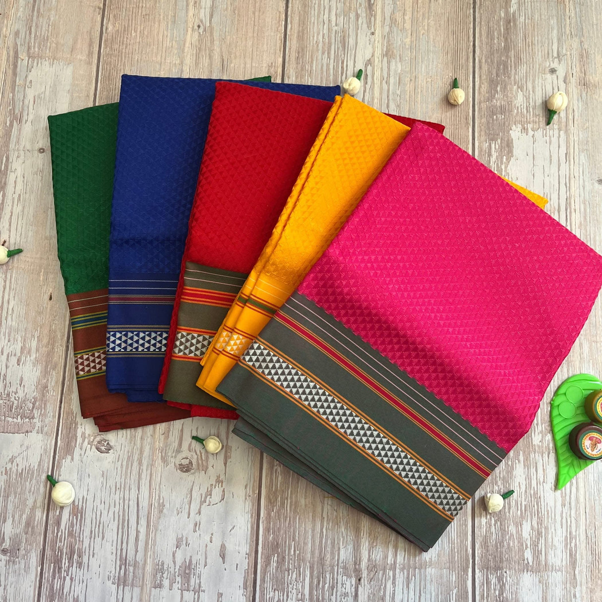Colorful folded sarees with patterned borders for traditional Khun cotton blouse pieces