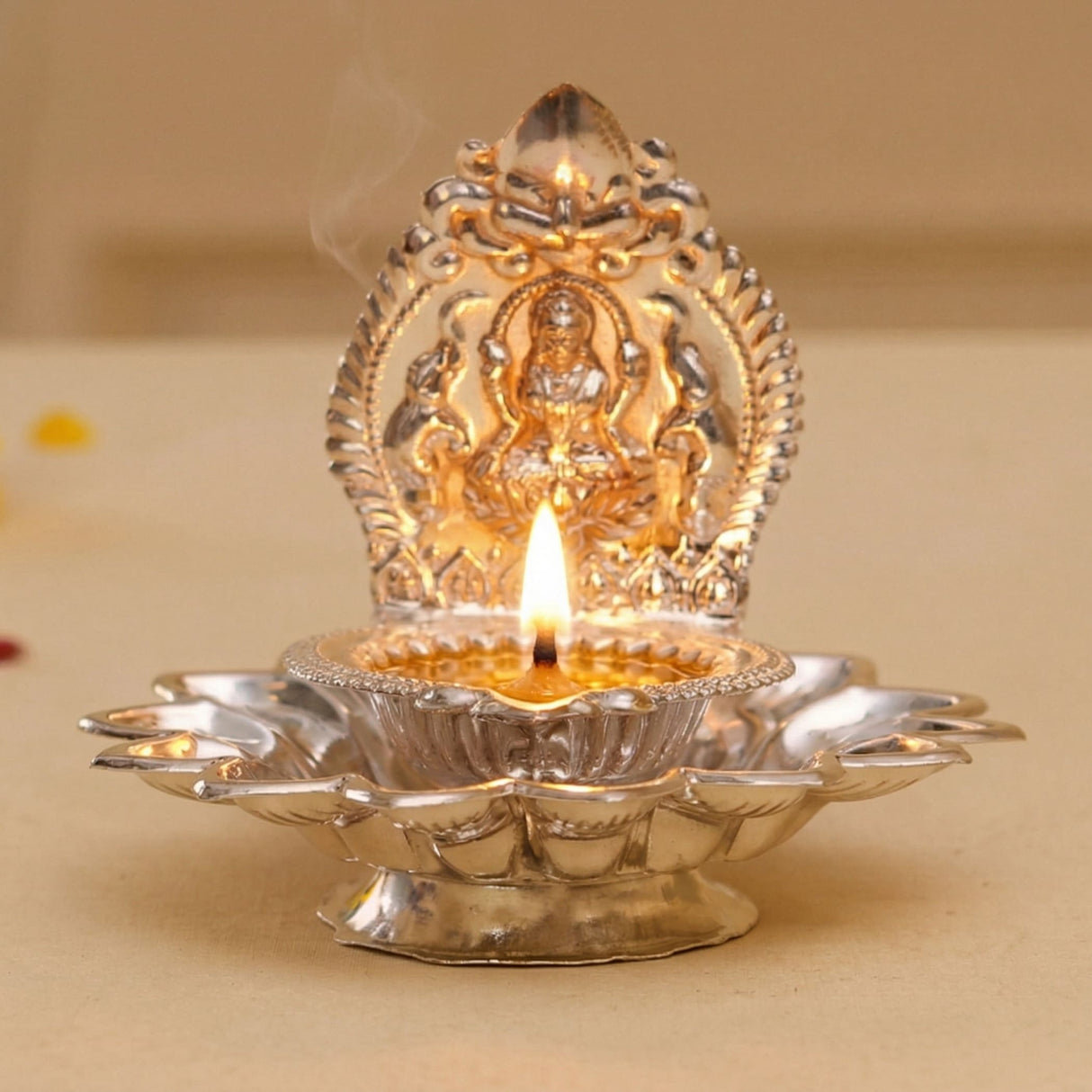 Silver and gold-plated metal diya with intricate deity design in varalakshmi vratham gift hamper for hindu pooja rituals