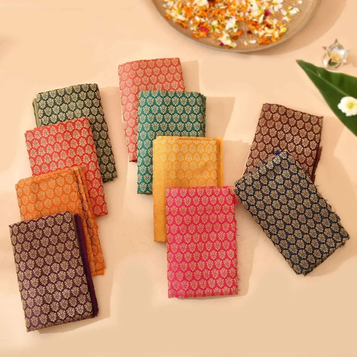 A collection of vibrant fabric squares in red green gold and purple featured in varalakshmi vratham gift hamper kit