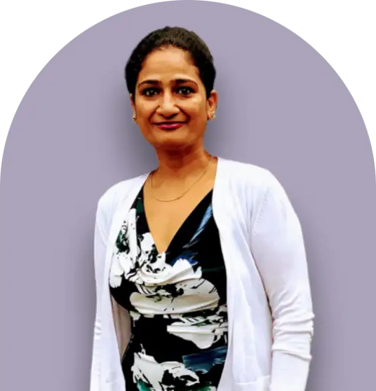 Woman wearing a white cardigan over a black and white patterned top.