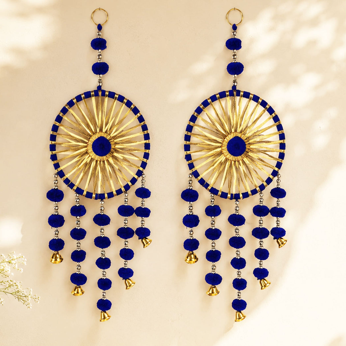 Blue and gold chandelier style earrings with intricate radial patterns pom pom accents and dangling bells for festive decor
