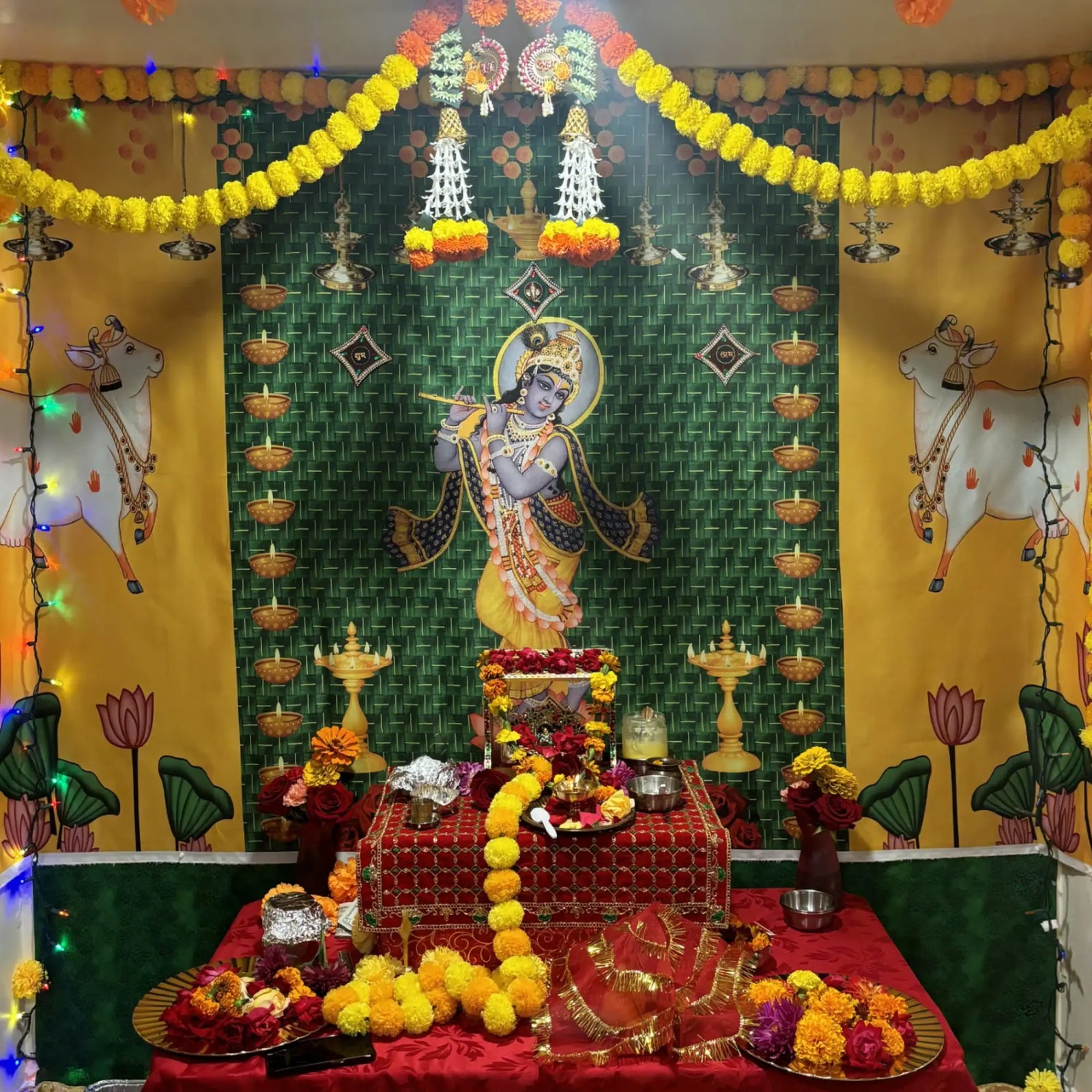 Golden Krishna statue in pooja backdrop decoration with red and gold accents.