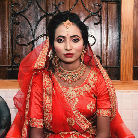 Close-up of a red bindi on a woman’s forehead with subtle festive elements in the background symbolize cultural ceremonies and aesthetic appeal.
