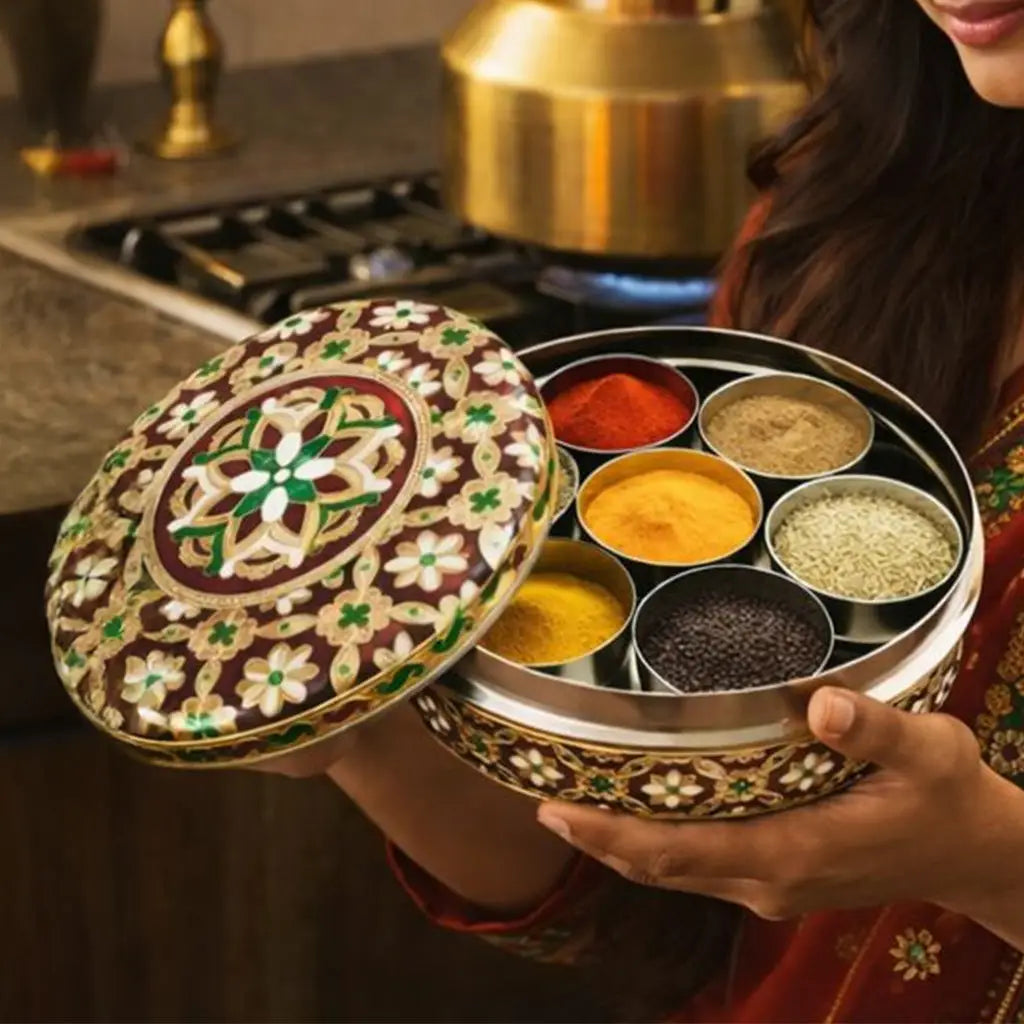 Ornate brown and gold enamel indian spice box with six compartments of colorful spices in metallic containers for masala dabba.