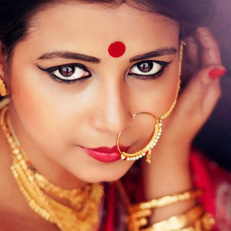 A woman showcases her beauty with red bindi, complemented by a distinctive nose ring, radiating sophistication.