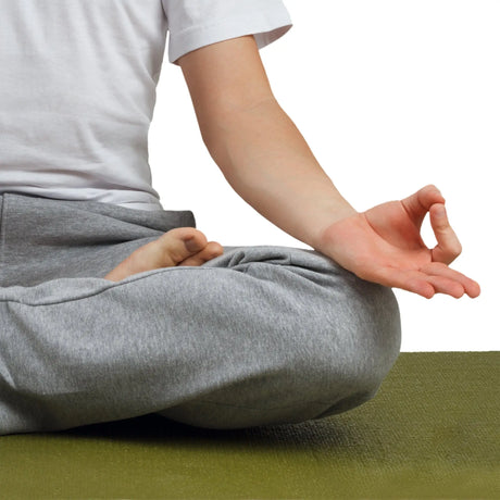 Man sitting calmly on a meditating mat in a relaxing posture.