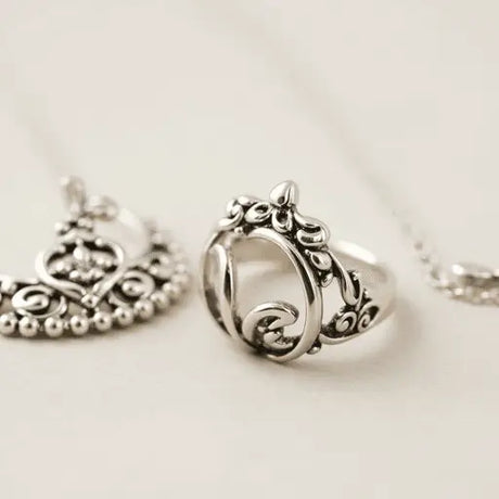 Close-up of elegant German silver jewelry, featuring shiny pieces and intricate designs, including an adjustable toe ring inspired by traditional Indian styles on a soft background.