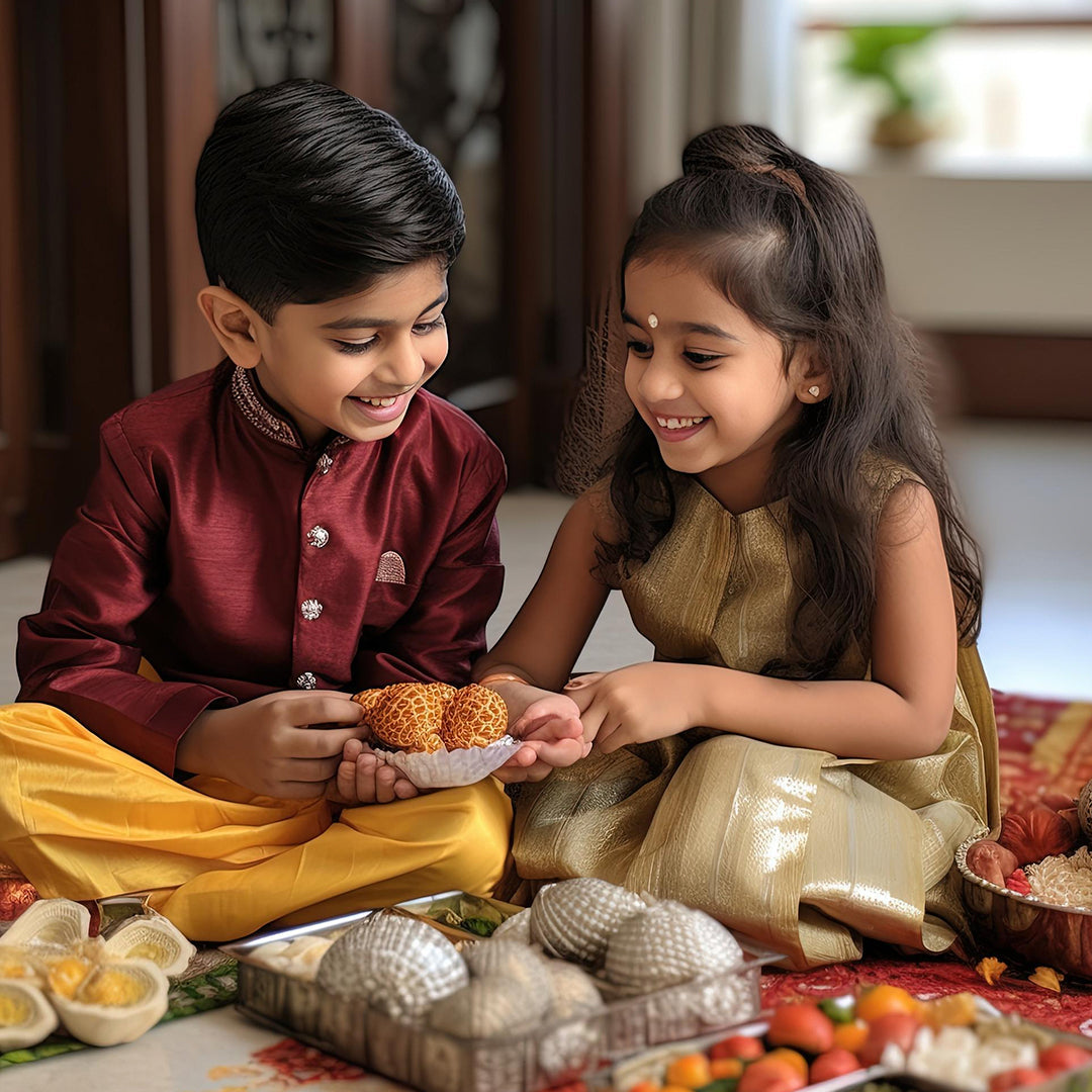 Two children in traditional Indian attire seated on the floor, enjoying a variety of colorful dishes spread before them.