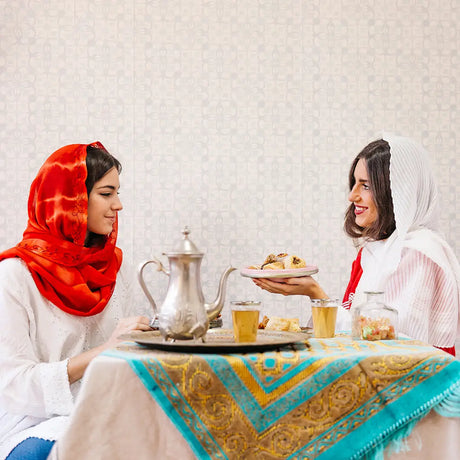 Two women in headscarves enjoying food at a table with a German silver bowl set for Ramadan decorations inspiration