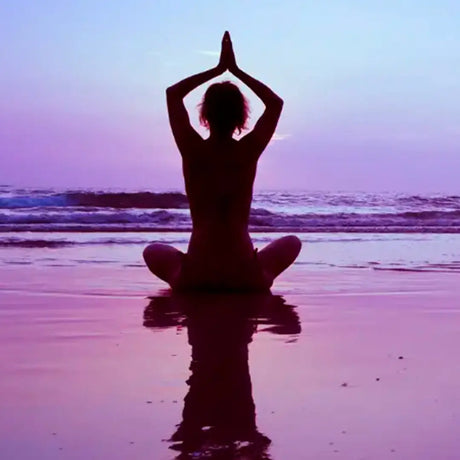 A woman practicing yoga on the beach during a serene sunset, embodying tranquility and connection with nature.