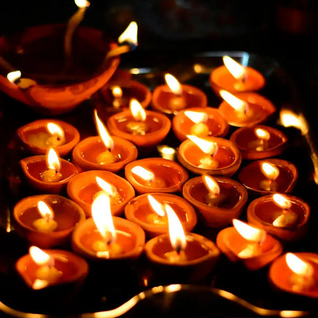 A tray filled with numerous small lit candles, creating a warm and inviting ambiance.