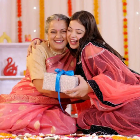 Two people embracing with a gift box during a South Indian saree function at a half saree ceremony