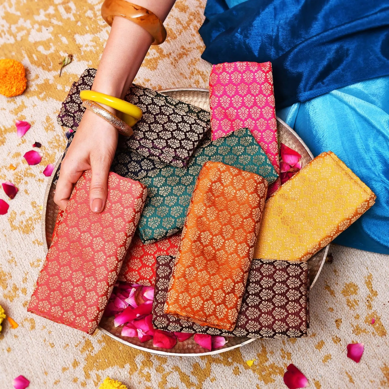 Colorful traditional Indian blouse fabrics arranged with marigold flowers and glowing lamps, creating a festive and elegant cultural display.