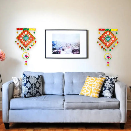 Light gray two-seater sofa with decorative throw pillows in modern interior with Indian wall art