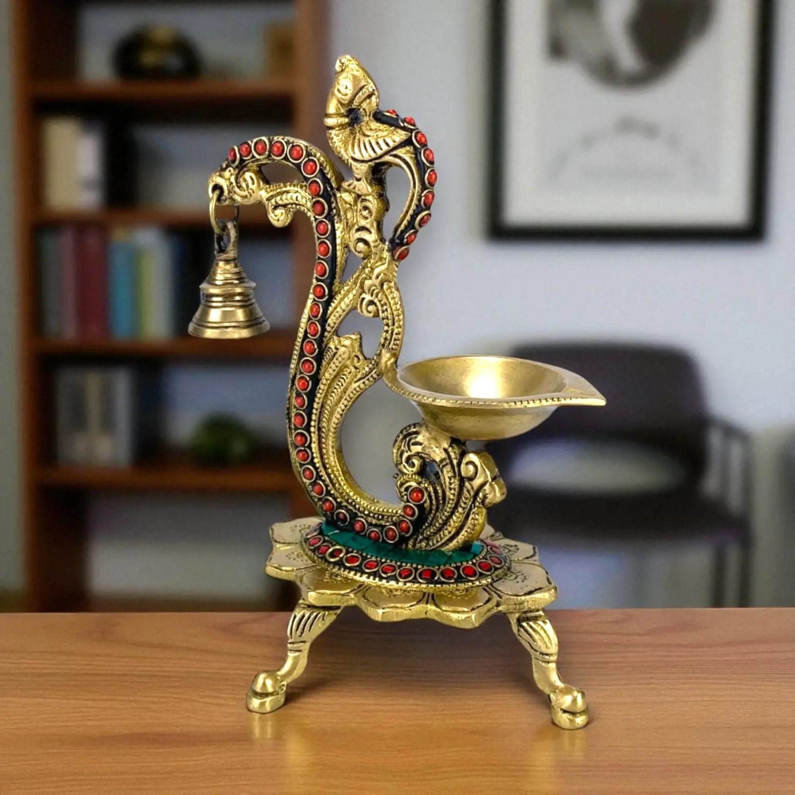 Ornate brass peacock diya with hanging bell, red and green accents, perfect for festive decor