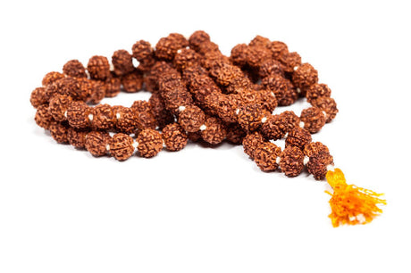 Close-up of a 108-bead Rudraksha mala on a wooden surface, softly illuminated by warm natural light, evoking peace and spiritual energy.