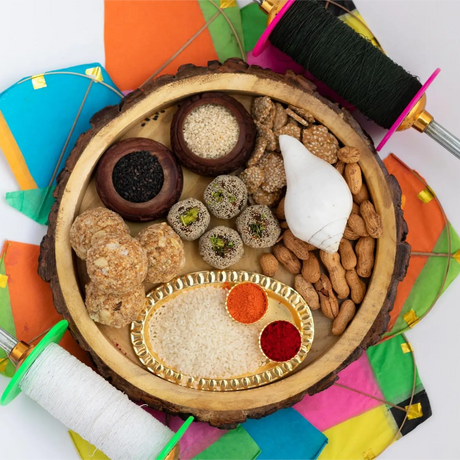 Festive outdoor table with traditional Indian foods during Makar Sankranti celebrations and colorful kites
