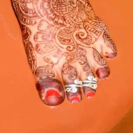 A woman's foot adorned with Toe Rings, showcasing detailed patterns and designs on her skin.