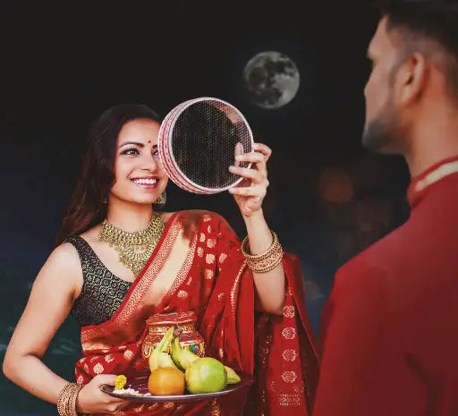 A beautifully arranged Karwa Chauth thali set featuring an assortment of colorful sweets, fresh fruits, and a shining diya (oil lamp).