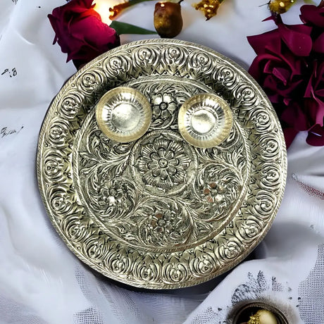 A silver plate adorned with two lit candles and a bouquet of vibrant flowers.