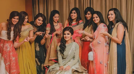 A joyful group of four individuals dancing at a Sangeet ceremony, two of Asian descent and two of Caucasian descent, all wearing colorful traditional attire. Th