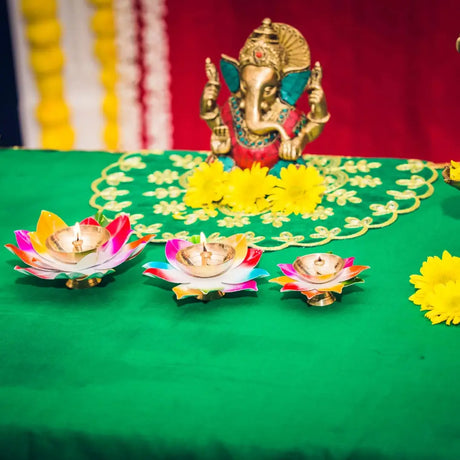 Golden oil lamp with ornate design held in hands with bangles, symbolizing lighting diyas in Indian tradition