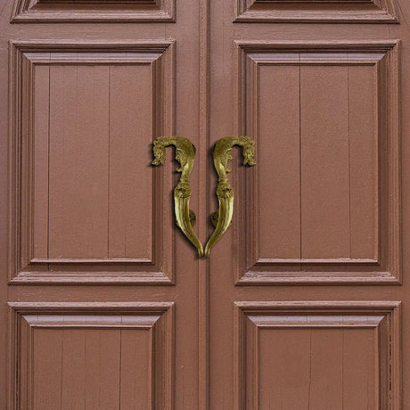 Ornate brass door handle shaped like letter B on brown door showcasing stylish upgrade