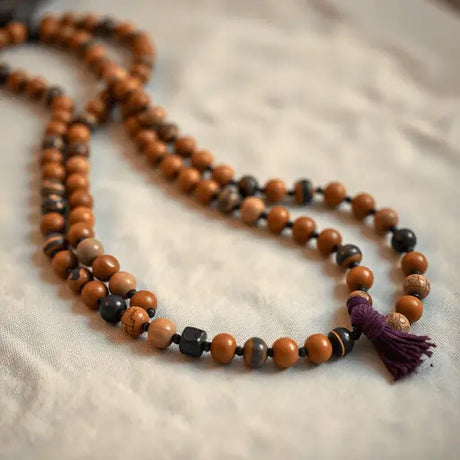 Close-up of traditional wooden and gemstone mala beads on soft fabric with warm lighting, evoking spirituality and mindfulness.