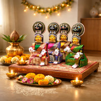 Decorative statues with colorful attire on a wooden platform, surrounded by flowers and candles, with 'Vara Lakshmi Vratam Collection' text.