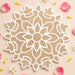 A delicate white laser-cut mandala design on a beige mdf 12 inch diy reusable rangoli mat with flower petals