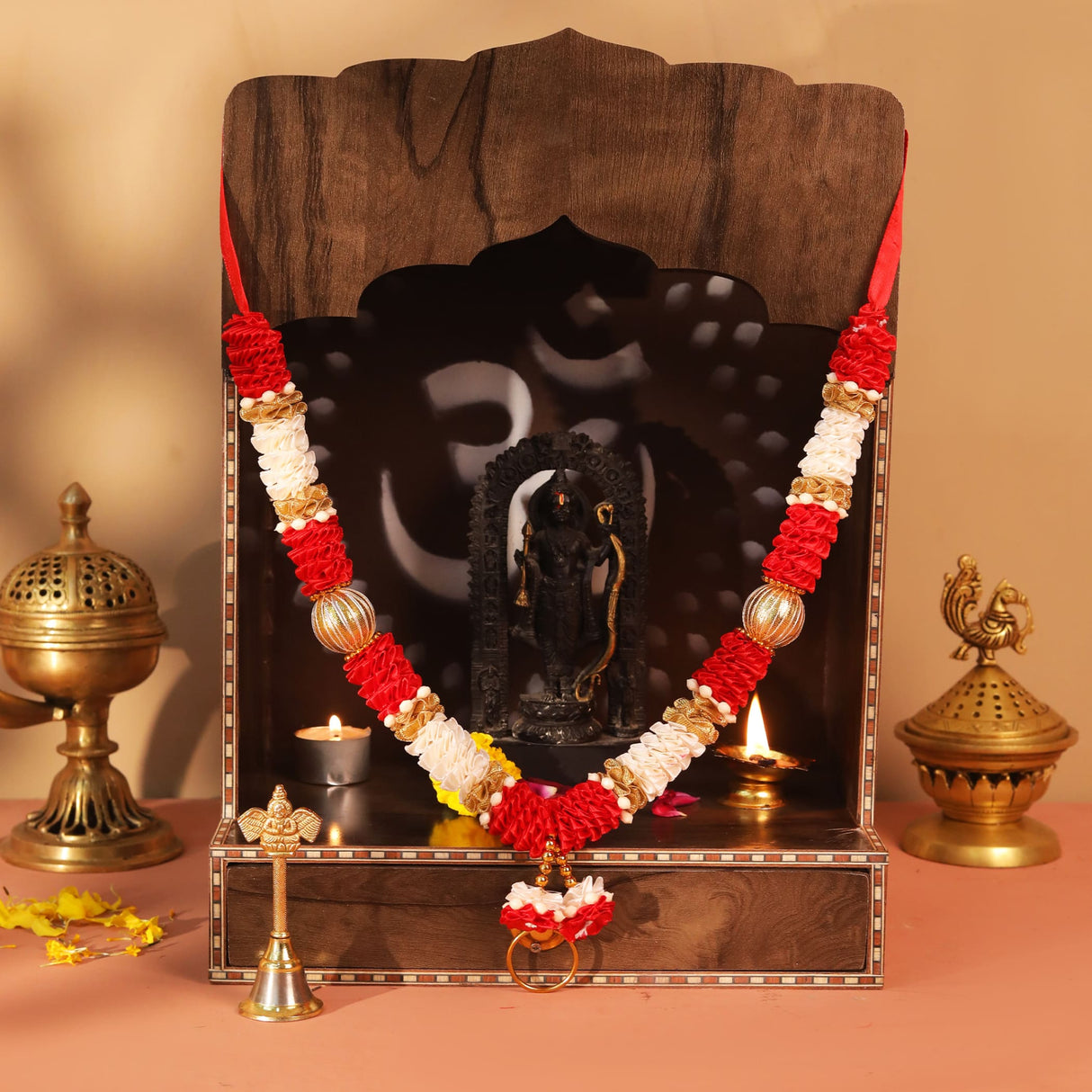 Red white floral garland with gold accents on wooden altar black deity statue