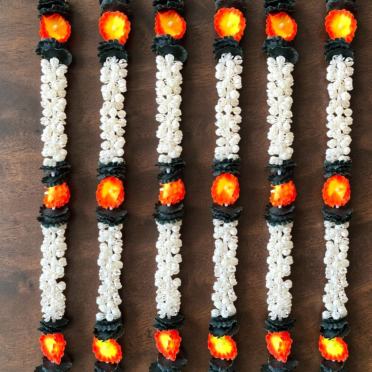 White and black artificial jasmine buds garland with glowing orange accents for festivals pooja and wedding decor