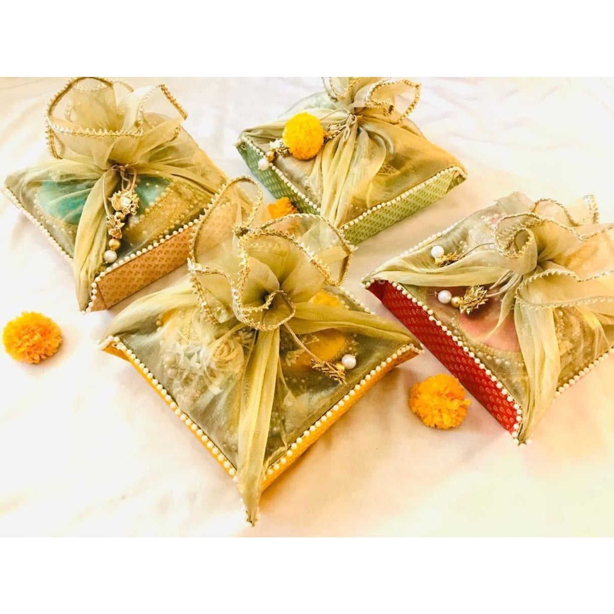 Golden and green fabric pouch with pom-poms, beads, and woven pattern for Indian gift packaging