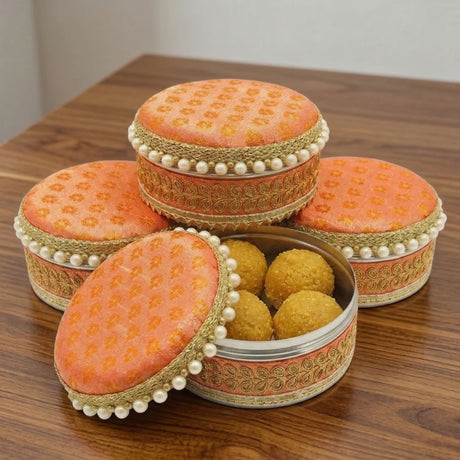 Ornate peach fabric lidded 4 ct stainless steel ladoo box with gold embroidery and pearl trim for festival sweets gift