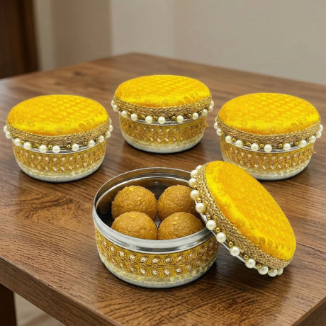 Yellow velvet-lidded stainless steel 4 ct ladoo box with gold embroidery and pearl accents containing golden sweets for festivals
