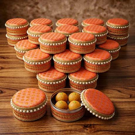 Ornate orange and gold steel ladoo boxes with pearl trim designed for traditional indian sweets festival gift packaging