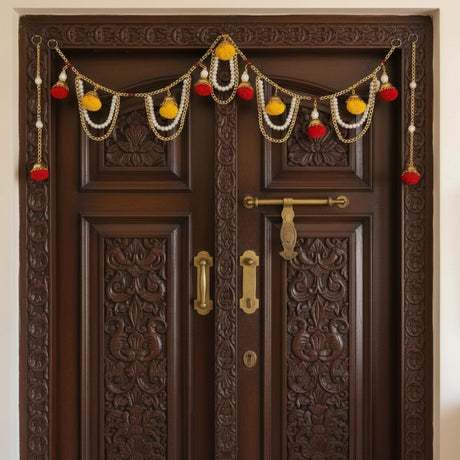 Dark brown wooden double door with ornate carvings and festive Indian door toran decor