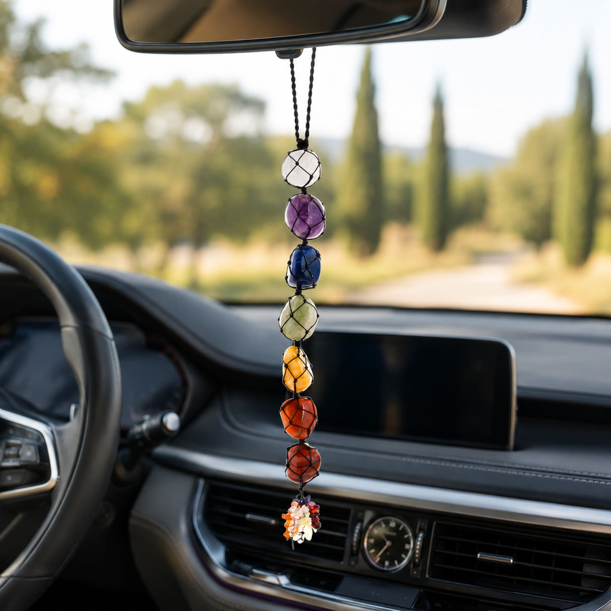 A seven-chakra-colored tumbled gemstone crystal car hanging ornament with black cord and flower charm for spiritual decor
