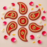 Red and gold paisley-shaped acrylic decorative appliqués with intricate floral patterns for diya floor rangoli decor