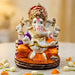Acrylic ganesh statue 2.25 inch with white body, vibrant orange and purple garments, gold jewelry, and golden crown for pooja and decor