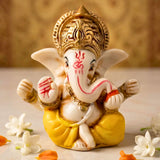 A detailed white and gold acrylic ganesha statue with red markings seated in a traditional pose for home and car decor