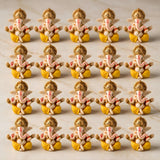 Acrylic ganesha idol in golden and yellow with pink elephant trunks and red markings for home temple and festive decor
