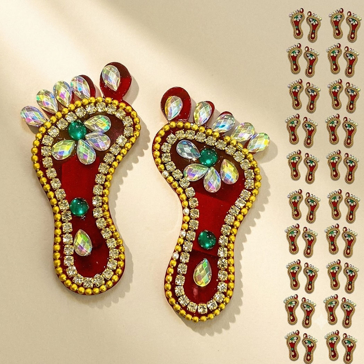 Red and gold embellished acrylic lakshmi charan paduka feet with iridescent crystals and green gemstones for diwali decor