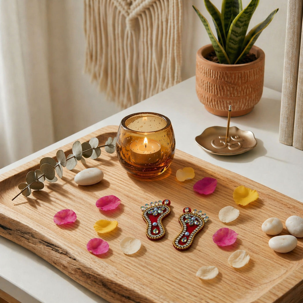 Amber glass candle holder with lit candle beside acrylic lakshmi charan paduka feet for diwali home temple decoration